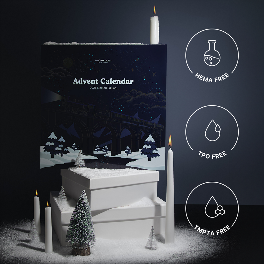 A dark navy advent calendar box with a winter forest illustration, styled with white candles, miniature trees, and stacked white boxes on a dark background. Three circular icons on the right read HEMA FREE, TPO FREE, and TMPTA FREE.